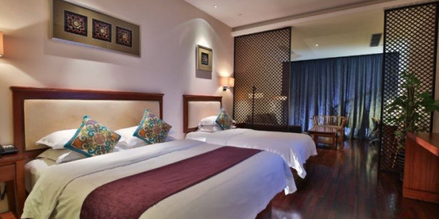 Interior of a hotel room with two beds and a television, showcasing a cozy and inviting atmosphere.